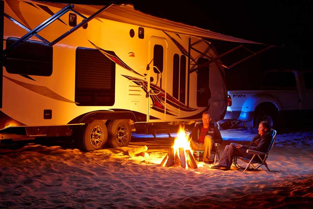 Image of RV Camping outside with a fire at night with a carefree of colorado awning