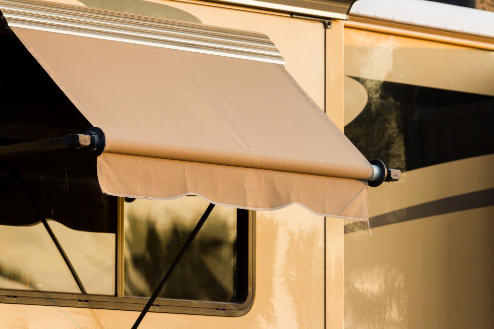 Close-up of a beige RV awning extended over a window on a motorhome – visual reference for measuring and selecting the correct RV awning size.