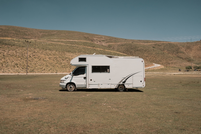 RV parked at a scenic campsite with slideout extended on a sunny day.